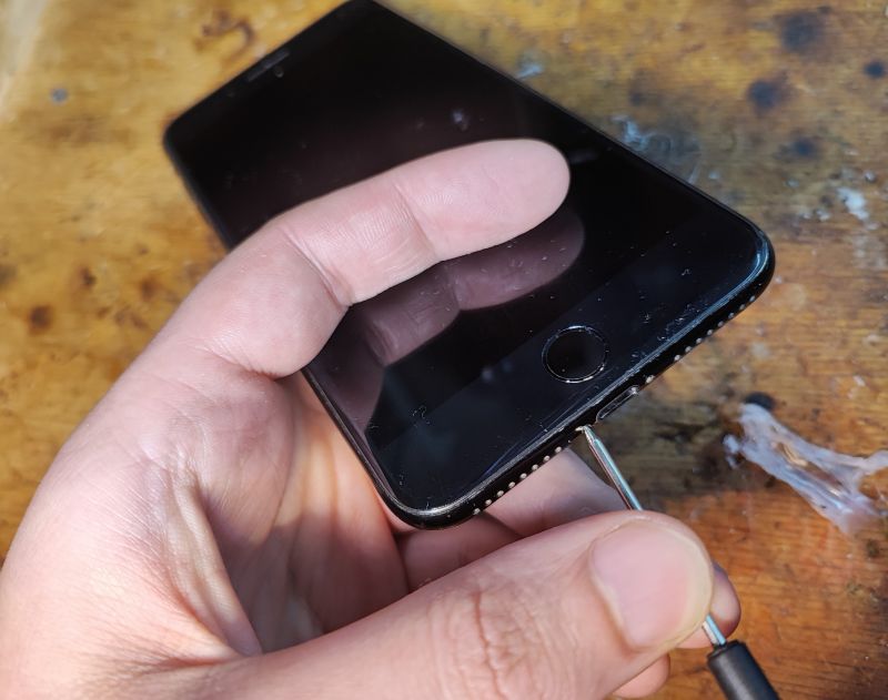 Unscrewing iPhone Screws A person unscrewing iPhone screws on a wooden surface
