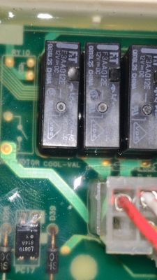 Zbliżenie na płytkę drukowaną z trzema przekaźnikami oznaczonymi F3AA012E oraz widocznymi przewodami i innymi elementami elektronicznymi.