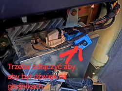 Złącza kabli i niebieskie gniazdo w samochodowym module audio z instrukcją na czerwono.