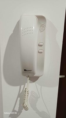 Biały domofon Genway z dwoma przyciskami zamontowany na ścianie.