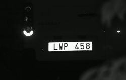 Zdjęcie tylnej części samochodu z widoczną tablicą rejestracyjną LWP 458, oświetloną w ciemności.