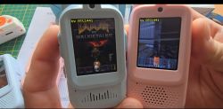 Two handheld devices with screens showing the game DOOM, held in hands on a desk.