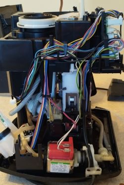 Wnętrze ekspresu do kawy z odsłoniętymi przewodami, pompą i modułem elektroniki