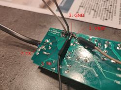 Garage Door Controller PCB with Soldered Wires Circuit board with soldered wires on pins labeled for TX, RX, GND, and VBAT.