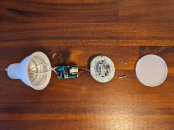 Disassembly of LED Bulb Dismantled LED bulb with parts on a wooden surface.
