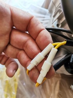 Dłoń trzymająca trzy żółte kable z białymi końcówkami przy silniku.
