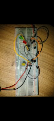 Płytka stykowa z układem elektronicznym zawierającym trzy świecące diody LED, przewody połączeniowe, tranzystory i inne elementy elektroniczne.