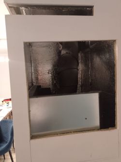 Interior of a fireplace enclosure with a visible flue pipe surrounded by metallic foil.