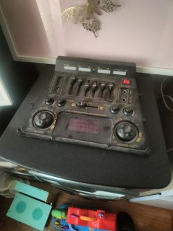 Mikser audio z pokrętłami i przełącznikami na czarnym stole.
