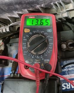Multimetr pokazujący napięcie 13.65V na akumulatorze.