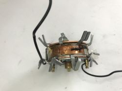 Electromagnet coil with copper winding and black wires on a white surface