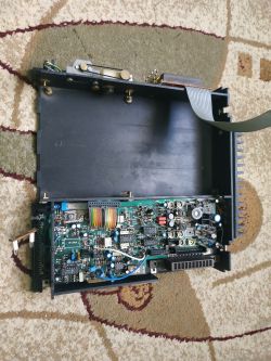 Widok wnętrza wieży stereo z odsłoniętą płytą główną na dywanie.