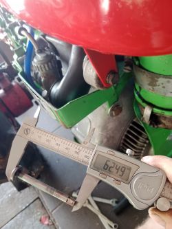 Cyfrowy suwmiarka mierząca średnicę elementu mechanicznego przy maszynie rolniczej, wskazuje 62,49 mm.
