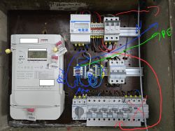Zdjęcie rozdzielnicy elektrycznej z widocznym licznikiem i kablami.