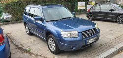 Blue Subaru Forester parked on a sidewalk.