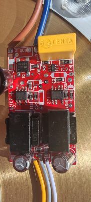 Płytka sterownika LED na czerwonym PCB z przekaźnikami, kondensatorami i podłączonymi przewodami