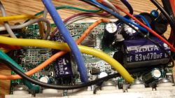 Zbliżenie na wnętrze sterownika roweru elektrycznego z widoczną płytką PCB, kondensatorami SZDLF oraz kolorowymi przewodami.