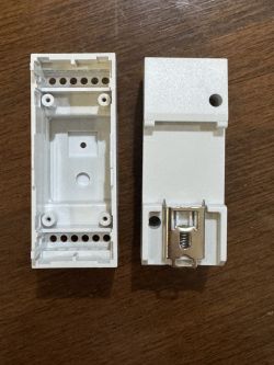 Two white plastic casing components on a wooden table.