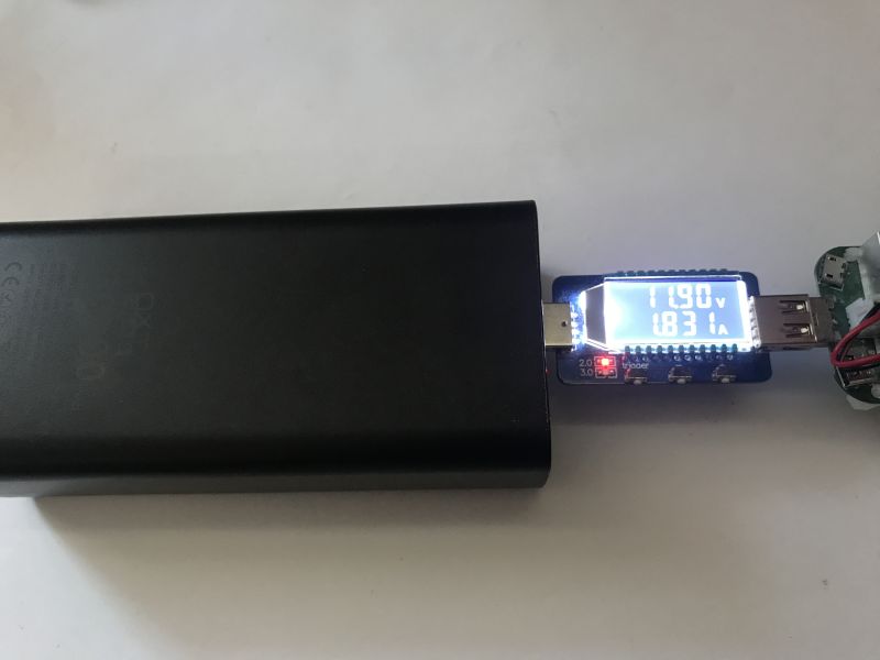 Power bank connected to USB voltage tester showing 11.90 V and 1.831 A
