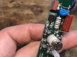 Electronic module with PIR sensor held in hand, visible capacitors and resistors