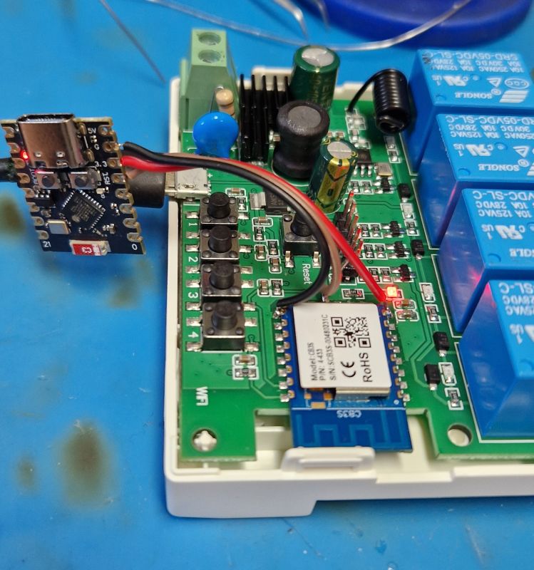 Wi-Fi relay module with USB flasher connected, on a blue work surface