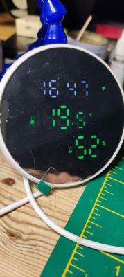 Digital thermometer with a display showing the current time, temperature, and humidity.