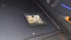 Gniazdo lampki w piekarniku oraz śrubokręt leżący obok na metalowej powierzchni.