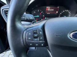 Close-up of a car steering wheel with control buttons and dashboard visible.