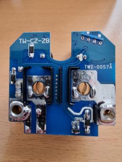 PCB with markings TW-CZ-ZB and TW2-0057A lying on a wooden surface.