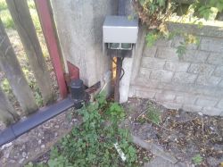Skrzynka z alucobondu z gniazdami elektrycznymi zamontowana na betonowym słupku przy bramie