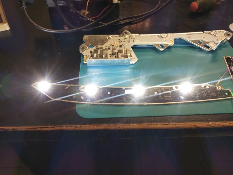 Leiterplatte mit vier hell leuchtenden LEDs auf einer Werkbank, daneben eine weitere elektronische Platine.