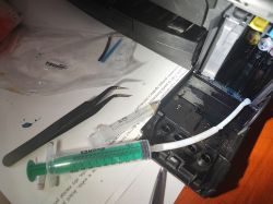 Cleaning the Internal Mechanism of a Brother Printer Syringe connected to the internal mechanism of a Brother printer using a tube.