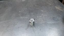 Zylindrisches Metallteil auf Tisch Zylindrisches Metallteil mit Loch, auf einem Stahltisch platziert.