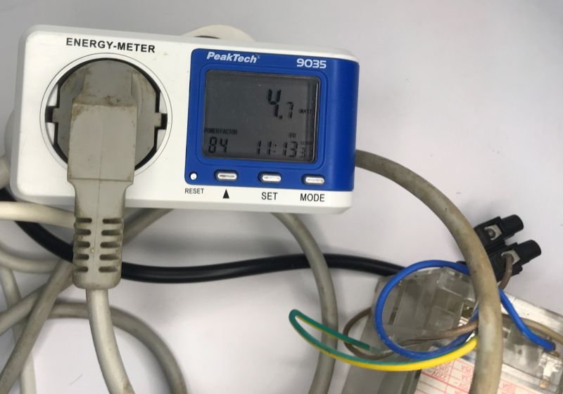 PeakTech 9035 energy meter with a plug inserted; display reads 4.7 W and power factor 0.84.