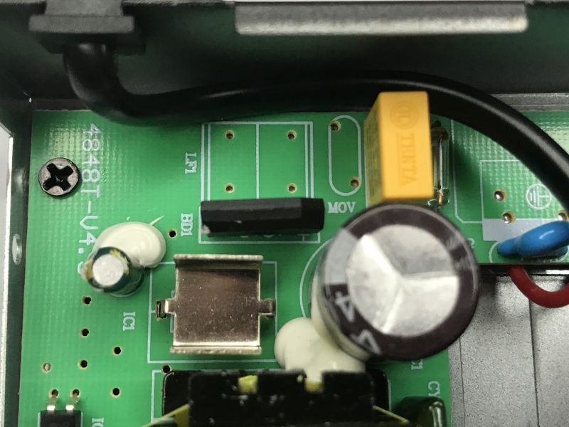 Close-up of power-supply PCB with electrolytic capacitor, MOV/fuse footprints, yellow capacitor, and wiring