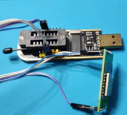 USB programmer with ZIF socket and connected PCB module on blue background
