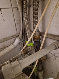 Close-up of pipes and cables with a green butterfly valve.