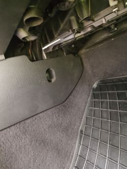 Wnętrze samochodu pod schowkiem z widoczną osłoną i kablem.