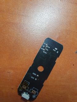 Printed circuit board of a sensor with visible markings and a connector.