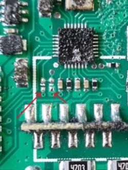 Close-up of PCB with two missing ferrite elements marked by red arrows