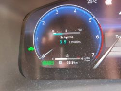 Zbliżenie na licznik hybrydowego auta, wskazanie średniego spalania 3,5 l/100 km
