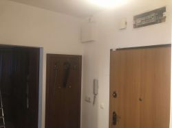 Przedpokój z drzwiami i otwartą rozdzielnicą elektryczną nad drzwiami.