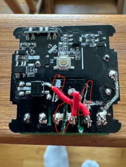Close-up of a circuit board with electronic components and red wires.