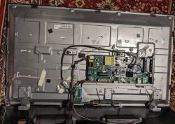 Rückseite eines offenen Fernsehers mit sichtbarem Inneren, einschließlich einer Hauptplatine und Kabeln.