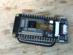 Sipeed M1s Dock Module with Camera on Wooden Background Sipeed M1s Dock module with camera and headers on a wooden background