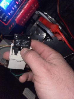 Przekaźnik w zabawkowym aucie elektrycznym Ręka trzymająca przekaźnik wewnątrz zabawkowego auta elektrycznego.