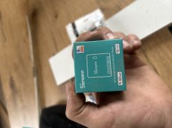 Pudełko sterownika WiFi Sonoff Mini trzymane w dłoni.