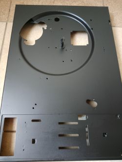 Metalowa obudowa urządzenia elektronicznego z okrągłym wycięciem i kilkoma otworami.