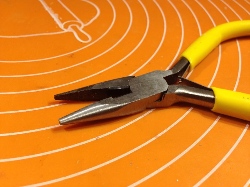 Kombinerki z żółtymi uchwytami na pomarańczowym tle.