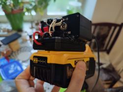 Zbliżenie na przenośną stację lutowniczą wykonaną z akumulatora DeWalt i czarnej obudowy z elektroniką.